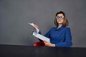 Frau im ein Blau Hemd sitzt beim das Tabelle Mappe im Hände Kopieren Raum foto