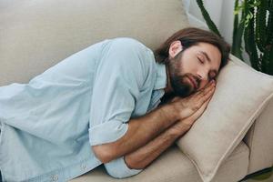 ein Mann Schlafen auf das Couch während das Tag ist müde und entspannt nach Stress und Gefühl schlecht. Stress beim arbeiten, Arm Schlaf und Gesundheit Probleme foto