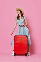 Frau Tourist im Hut mit rot Koffer Passagier Lebensstil Rosa Hintergrund foto