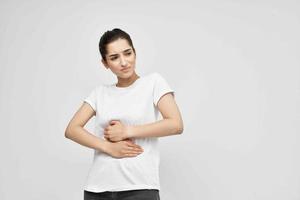 Frau im Weiß T-Shirt Bauch Schmerzen Behandlung zum Beschwerden foto
