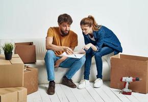 Mann und Frau sitzen auf Couch Kisten Werkzeuge sich ausruhen foto