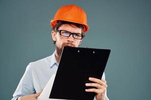 Mann Arbeiter mit Unterlagen im Hände tragen Brille Orange Helm Sicherheit Fachmann foto