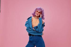 Porträt von ein charmant Dame lila Haar Mode Brille Denim Kleidung Rosa Hintergrund unverändert foto