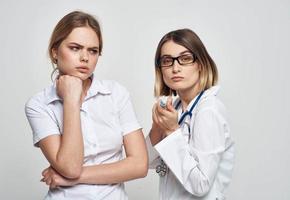 ein Krankenschwester im ein medizinisch Kleid hält ein Spritze im ihr Hand und ein geduldig auf ein Licht Hintergrund foto