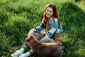 Frau glücklich lächelnd beim spielen mit ihr wenig Hund draußen auf frisch Grün Gras im das Sommer- Sonnenschein ihr und ihr Hund Gesundheit, Gesundheit Konzept und rechtzeitig Behandlung zum Insekten Zecken und Tick Flöhe foto