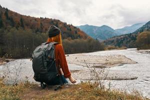 Frau im Herbst im das Berge mit ein Rucksack auf ihr Schultern Reise Tourismus Fluss foto