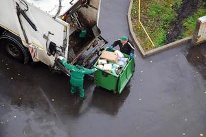 Müll Entfernung im Wohn Bereich, Müll Männer Wird geladen Haushalt Müll im Müll LKW foto