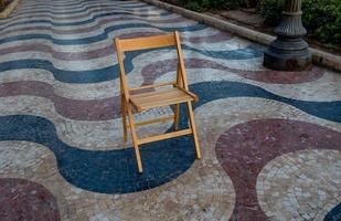 Erklärung Promenade im alicante Spanien Wahrzeichen mit hölzern leeren Stuhl auf Mosaik foto