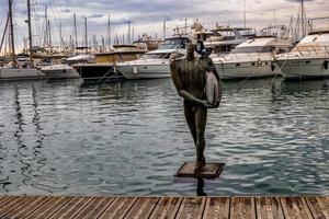 Statue von ein Surfer im das Hafen von alicante Spanien mit Tauben städtisch Landschaft foto