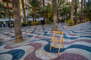 Erklärung Promenade im alicante Spanien Wahrzeichen mit hölzern leeren Stuhl auf Mosaik foto