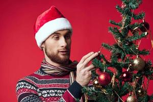 gut aussehend Mann mit ein Baum im seine Hände Ornamente Urlaub Spaß rot Hintergrund foto