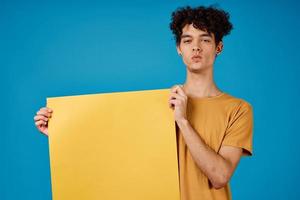 Kerl mit lockig Haar von Gelb Astern im seine Hände Studio Blau Hintergrund foto