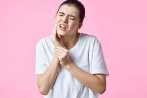 Frau im Weiß T-Shirt halten ihr Hals Schmerzen Probleme Rosa Hintergrund foto