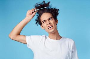 ein Mann im ein Weiß T-Shirt lockig Haar stecken Kamm Emotionen foto