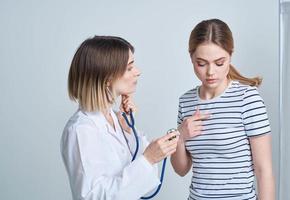 Arzt Frau im medizinisch Kleid mit Stethoskop hört zu zu Patienten Herz foto