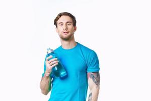 Mann im ein Blau T-Shirt mit ein Flasche von Wasser im seine Hand auf ein Weiß Hintergrund Kopieren Raum foto