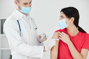 das Arzt macht ein Injektion in das Patienten Arm mit ein medizinisch Maske planen covid foto