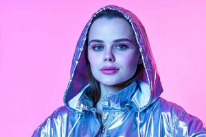 attraktiv Frau Silber mit Kapuze Jacke bilden Rosa Hintergrund Neon- foto