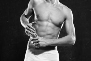 männlich Athlet im Weiß kurze Hose aufgeblasen Körper Bodybuilder das dunkel Hintergrund foto