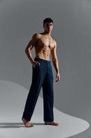 Sport Kerl im Jeans und Stiefel auf ein grau Hintergrund nackt Muskeln Bauch Torso foto