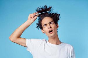 ein Mann im ein Weiß T-Shirt lockig Haar stecken Kamm Emotionen foto