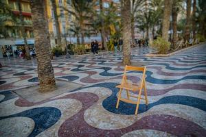 Erklärung Promenade im alicante Spanien Wahrzeichen mit hölzern leeren Stuhl auf Mosaik foto