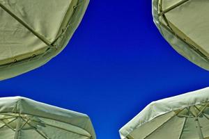 kunstvoll Hintergrund mit Regenschirme gegen das Hintergrund von ein Blau wolkenlos Himmel auf ein heiß Sommer- Tag beim das Strand foto