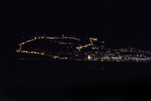 Nacht Aussicht von das Türkisch Stadt von Alanya mit Beleuchtung auf das Hügel foto