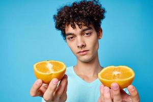 Mann mit lockig Haar halten Orangen Obst Blau Hintergrund foto