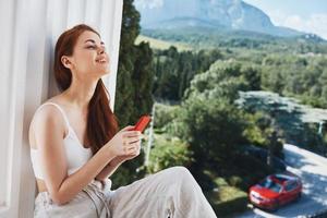 Porträt Frau mit ein rot Telefon Terrasse draussen Luxus Landschaft Freizeit Entspannung Konzept foto