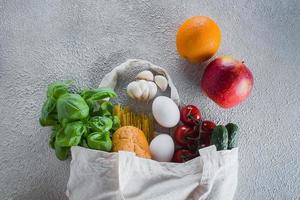 wiederverwendbar Tasche mit Lebensmittel. Tasche Tasche. Basilikum, Tomaten Kirsche, Knoblauch im Stoff Tasche. oben Aussicht foto