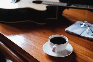 Kaffee und Gitarre auf einem Schreibtisch