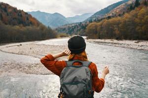 Frau Reise im das Berge auf Natur im Herbst in der Nähe von das Fluss und Rucksack Hut Sweatshirt Ferien foto