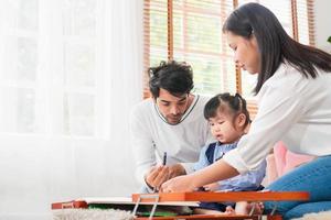 asiatisch Familie spielen im das Leben Zimmer, Kind Mädchen Tochter Mutter und Vater abspielen Spielzeug im das Haus, Eltern und Tochter spielen beim Zuhause foto