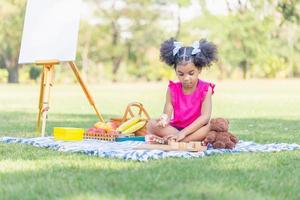 Kind Mädchen spielen mit hölzern Spielzeug draußen, süß wenig Mädchen abspielen Spielzeug im das Garten foto