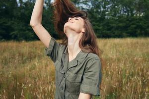 Frau im Grün Overall hält ihr Haar suchen oben frisch Luft foto