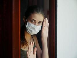 Frau im medizinisch Maske suchen aus das Fenster Nahansicht Quarantäne foto