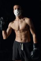 Athlet im medizinisch Maske und im Boxen Handschuhe auf isoliert Hintergrund abgeschnitten Aussicht von Bodybuilder foto