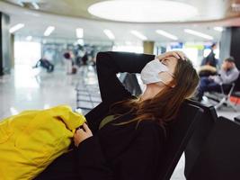 Frau mit geschlossen Augen medizinisch Maske Flughafen warten Passagier foto
