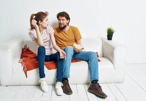 Mann und Frau auf das Couch drinnen chatten freunde Popcorn foto