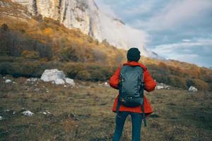 Frau Modell- im ein rot Jacke mit ein Rucksack im das fallen draußen warm Hut gefallen Blätter foto