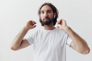 stilvoll Mann im ein Weiß T-Shirt mit kabellos Kopfhörer im seine Ohren haben Spaß Hören zu Musik- Lächeln auf ein Weiß Hintergrund Lebensstil foto