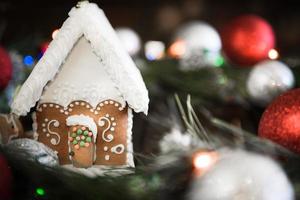 Lebkuchenhaus in der weißen Glasur auf dem Hintergrund der Weihnachtsdekoration foto