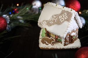 Lebkuchenhaus in der weißen Glasur auf dem Hintergrund der Weihnachtsdekoration foto