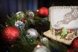 Lebkuchenhaus in der weißen Glasur auf dem Hintergrund der Weihnachtsdekoration foto