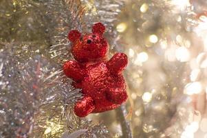 abstrakter Hintergrund von glitzernden Bokeh-Lichtern mit unscharfem Ornament auf dem silbernen Weihnachtsbaum im Vordergrund foto