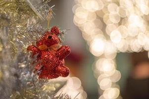 abstrakter Hintergrund von glitzernden Bokeh-Lichtern mit unscharfem Ornament auf dem silbernen Weihnachtsbaum im Vordergrund foto