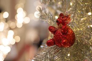 abstrakter Hintergrund von glitzernden Bokeh-Lichtern mit unscharfem Ornament auf dem silbernen Weihnachtsbaum im Vordergrund foto
