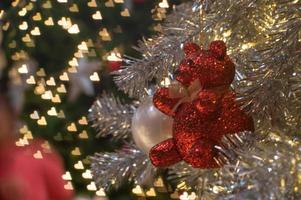 abstrakter Hintergrund von glitzernden Bokeh-Lichtern mit unscharfem Ornament auf dem silbernen Weihnachtsbaum im Vordergrund foto
