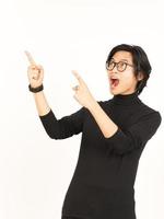 zeigen Produkt und zeigen Seite mit Zeigefinger mit Beeindruckend Gesicht von gut aussehend asiatisch Mann foto